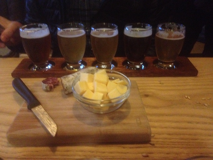 Tábua de queijos e salame ao lado de um sampler com cinco tipos de cerveja em um bar em Amsterdã, Holanda