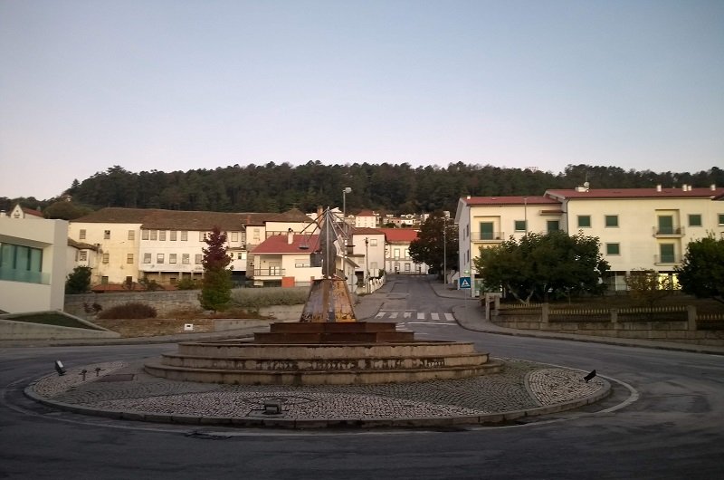 Rótula em cidade histórica de Portugal. Atrás dela podem ser vistas casinhas brancas com telhas cor de barro.